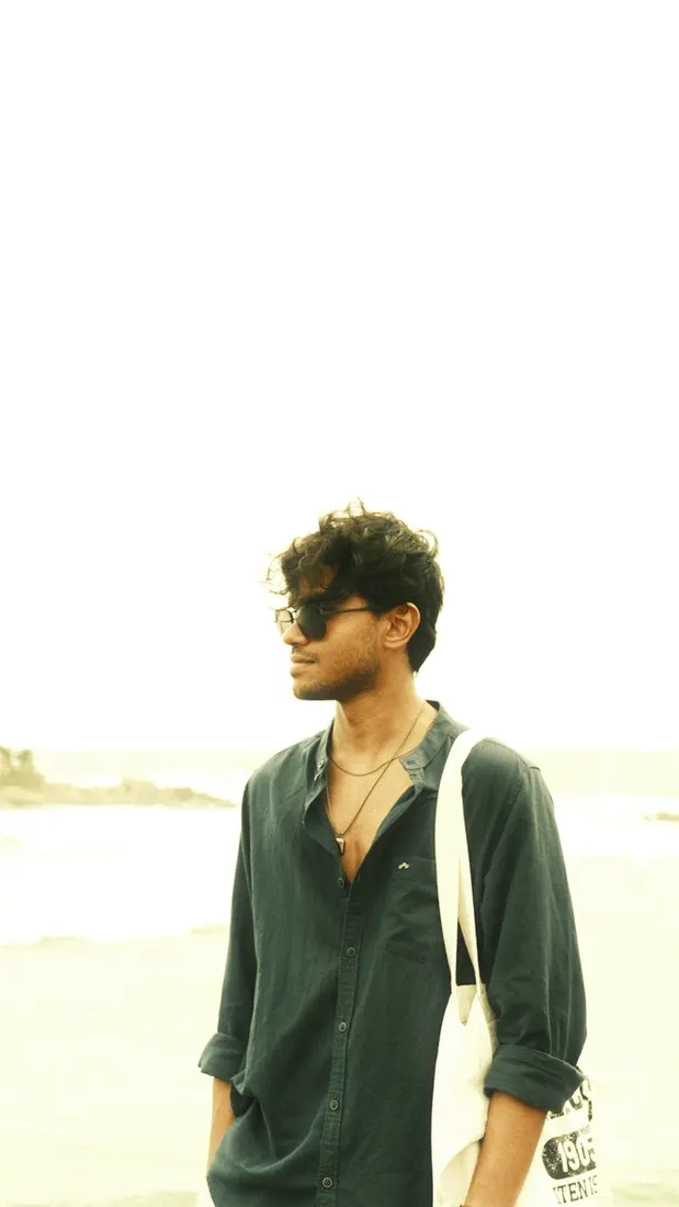 A man in sunglasses and a dark shirt on a bright beach