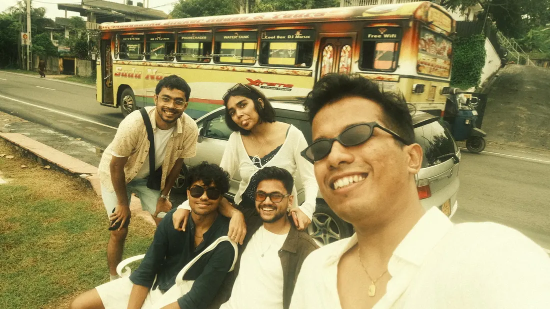 A group selfie by the roadside with a painted bus behind