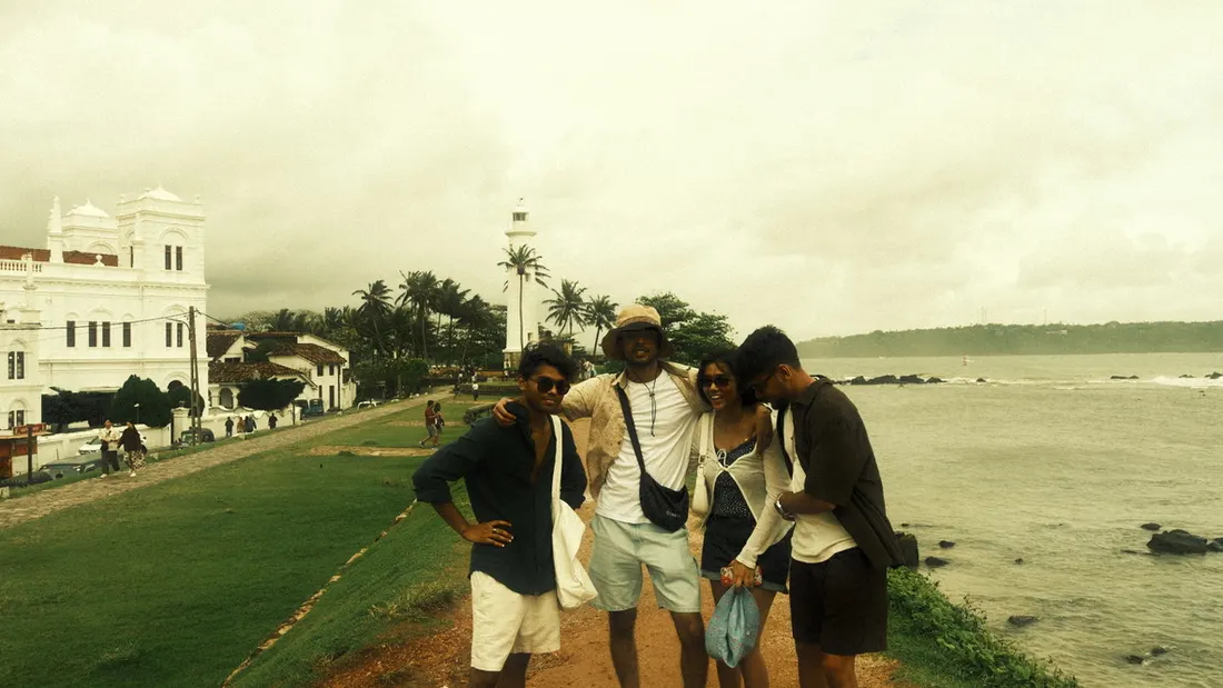 Four friends on grassy ramparts above the sea, a lighthouse behind them
