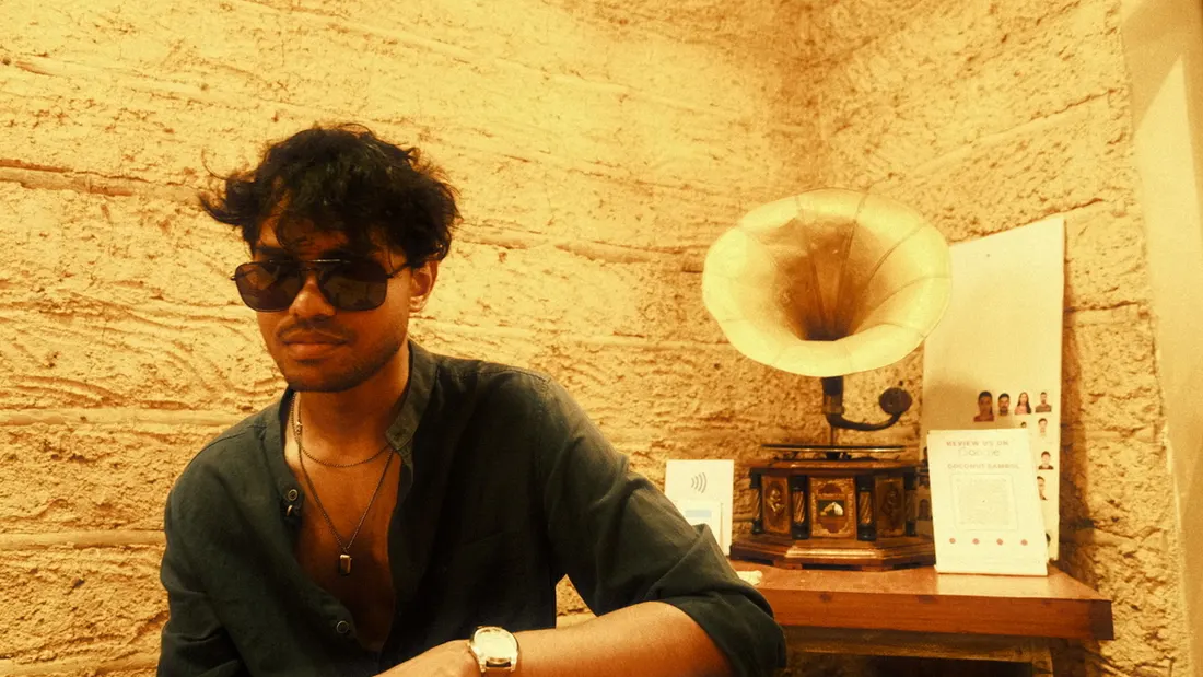 A man in sunglasses seated beside an antique gramophone
