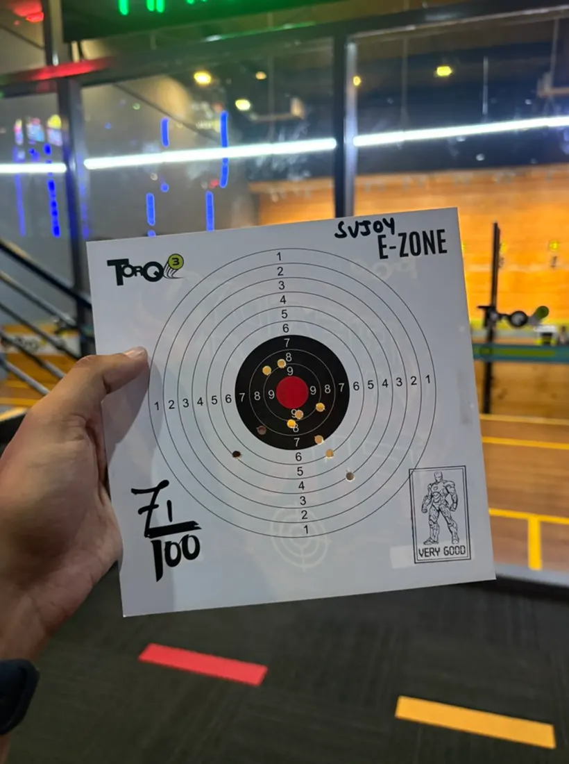 A paper shooting target held up at a range, most shots near the centre, stamped very good